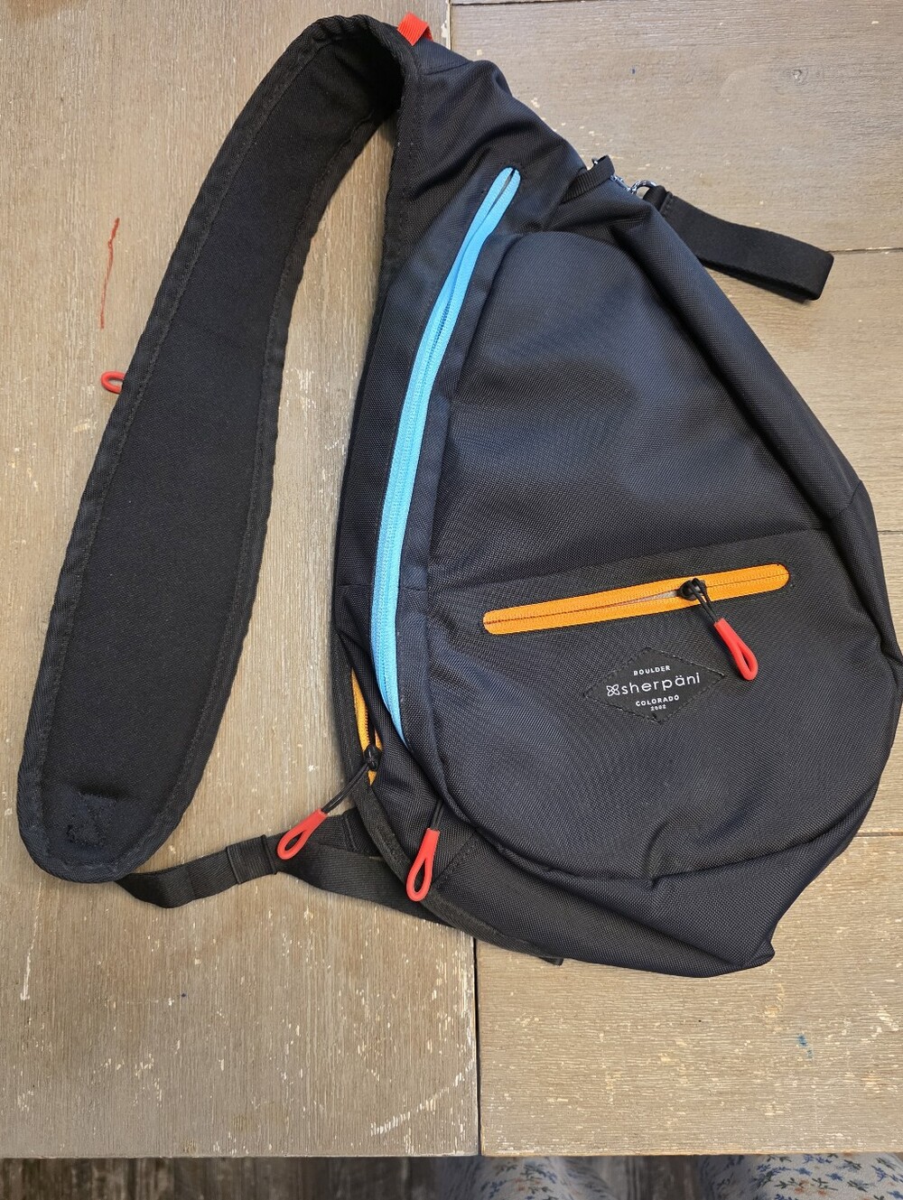 Sherpani black sling bag with blue and orange accents